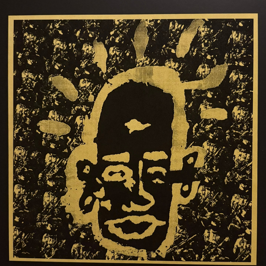 A square black and gold art print featuring a stylized face with radiating gold shapes on a textured black background, bordered by a gold frame against a dark backdrop.