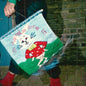 Person holding a colorful embroidered pillow with a cat design and text.