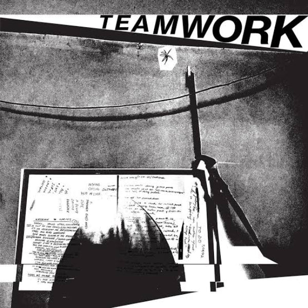 Black and white graphic print featuring the word 'TEAMWORK' in bold letters at the top, above a high-contrast abstract scene with a chalkboard, chalk, and handwritten notes.