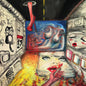 Abstract artwork with a face, colorful patterns, and a red tongue in a tunnel-like setting.
